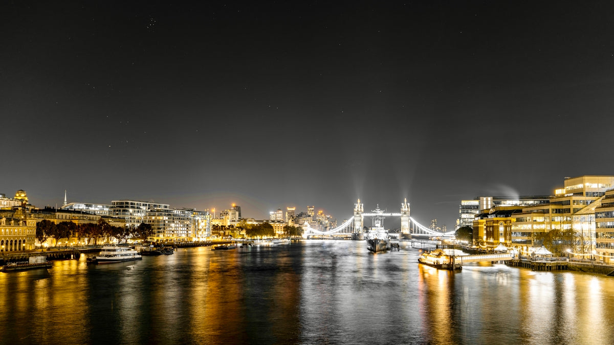 a night view of a river with a bridge in the background