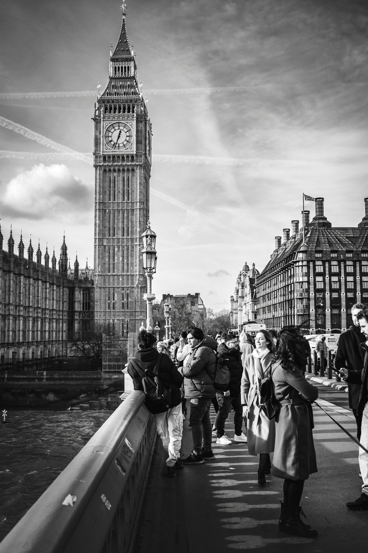 a group of people standing on a bridge next to a clock tower