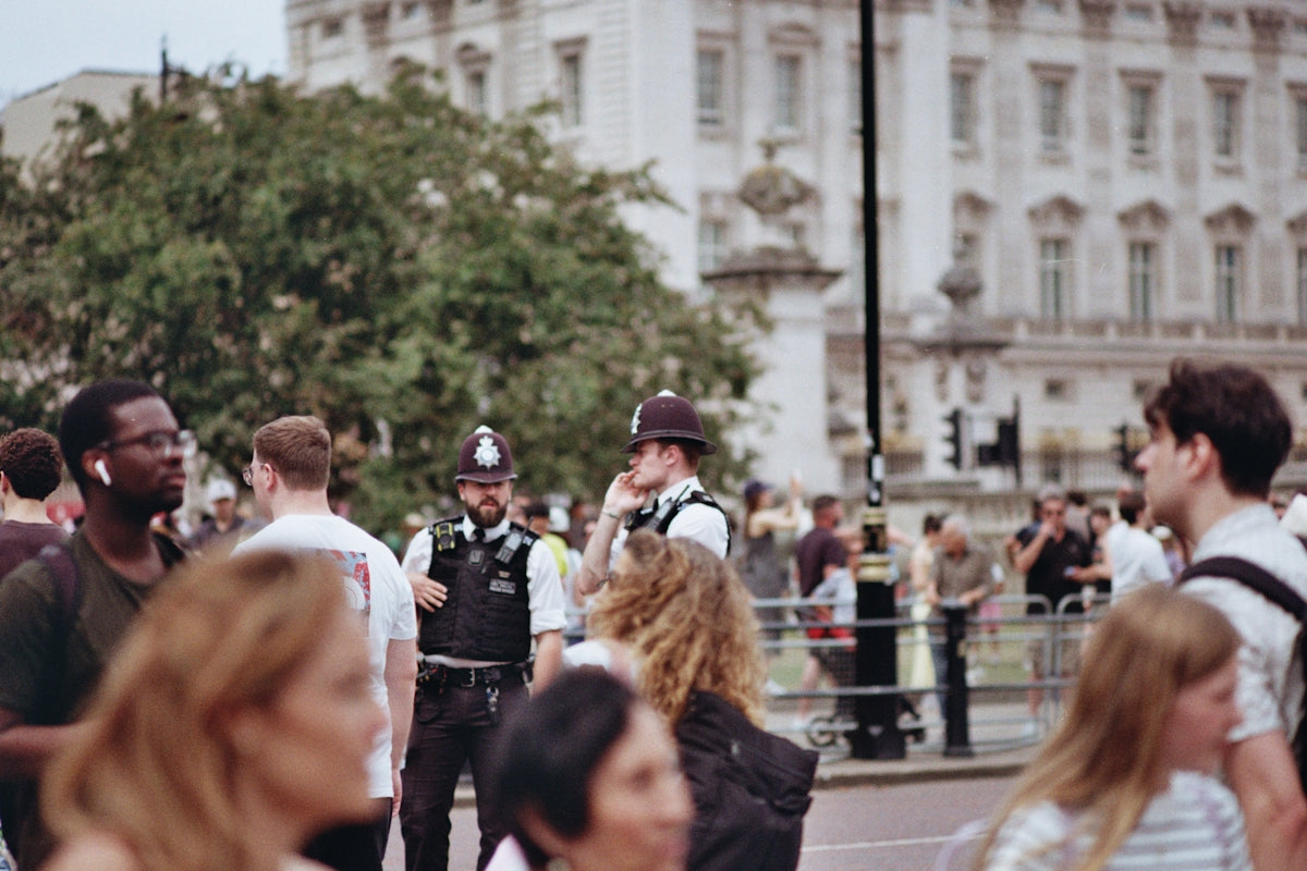 People and police officers near a grand building.