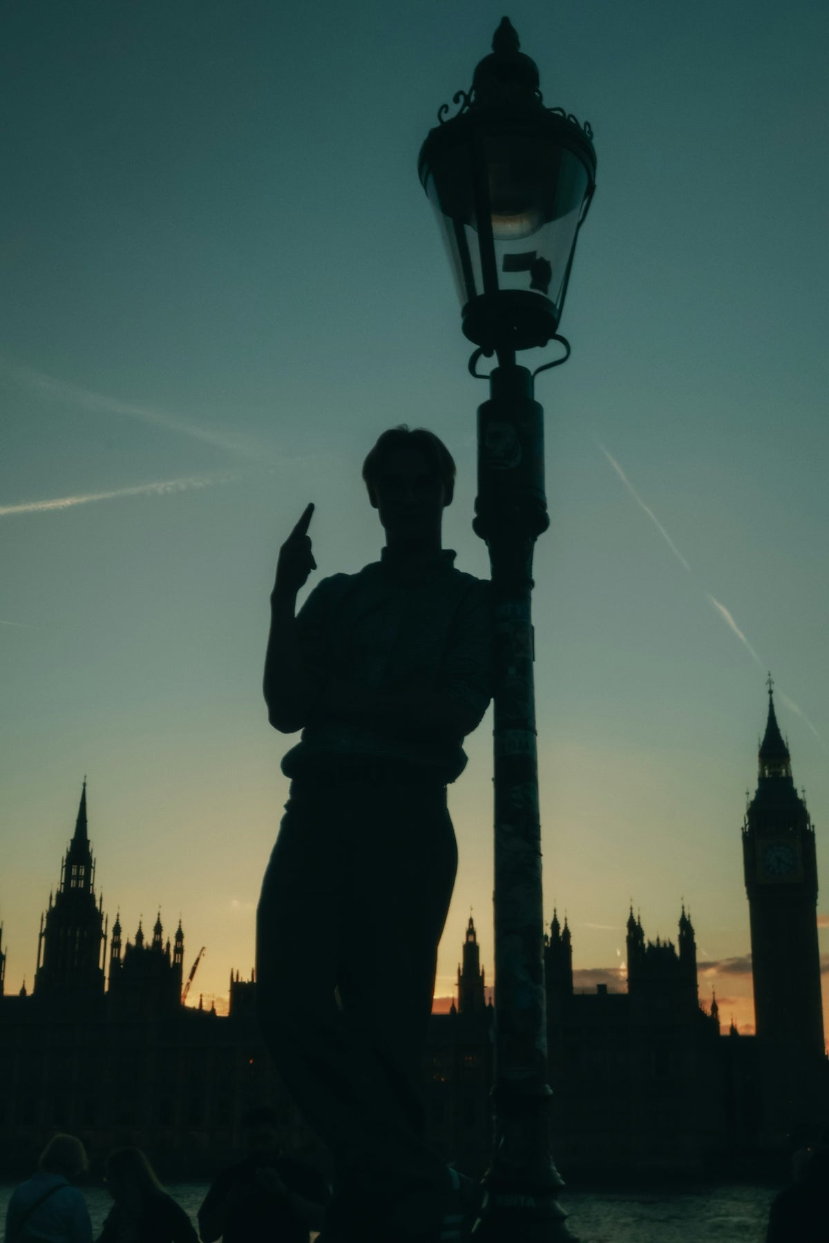 Silhouette of person and lamppost with london skyline at sunset